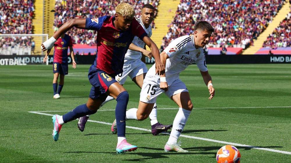 Lamine Yamal y Arda Güler pelean por un balón durante el último Clásico de esta temporada entre el Barcelona y el Real Madrid, bajo la mirada, en el fondo, de Kylian Mbappé. Lamine Yamal y Arda Güler pelean por un balón durante el último Clásico de esta temporada entre el Barcelona y el Real Madrid, bajo la mirada, en el fondo, de Kylian Mbappé.