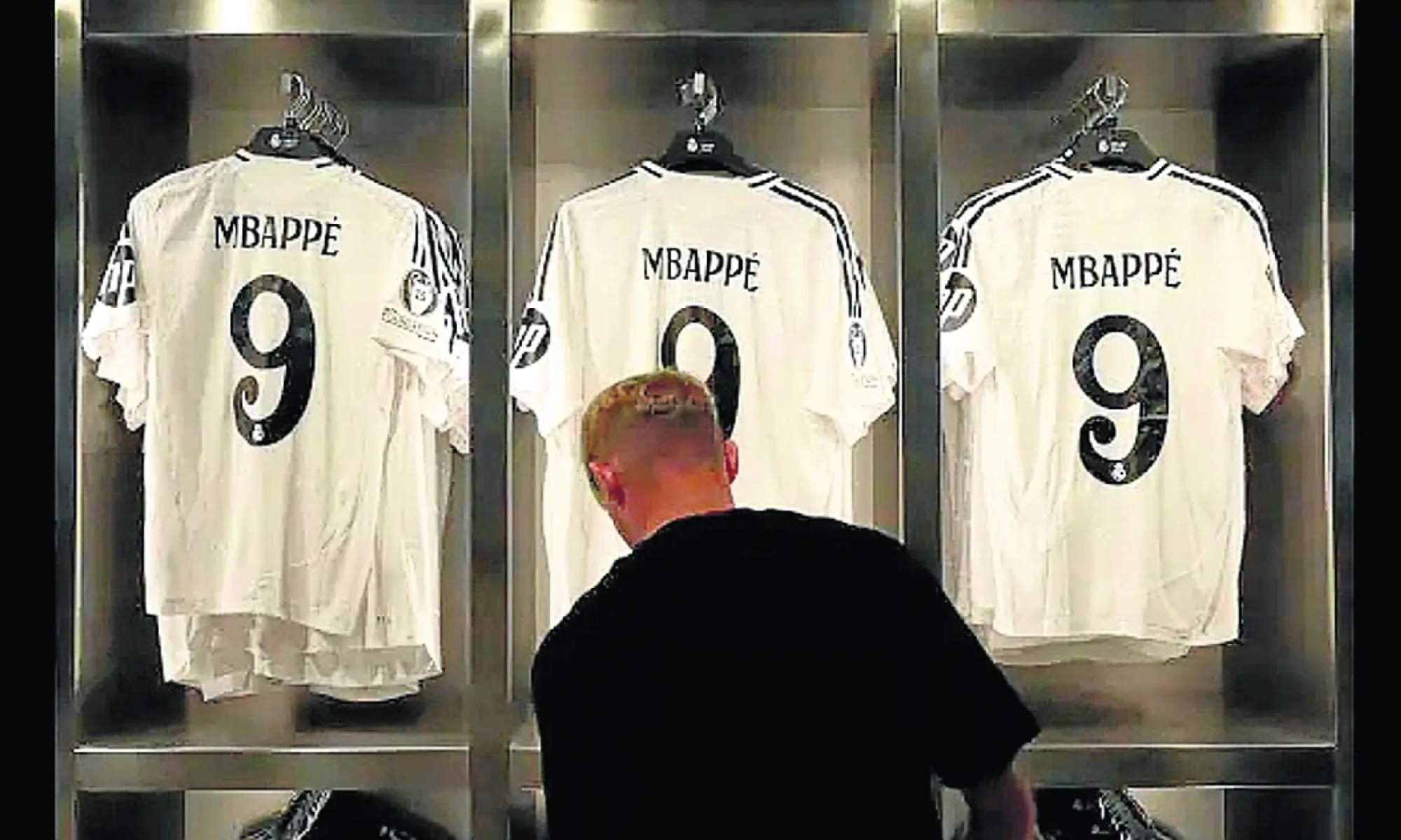 Un hombre, en una tienda oficial del Real Madrid, observando las camisetas de Kylian Mbappé.